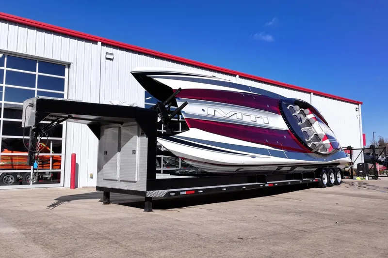 Slide: The Image of 2016 MTI 48 boat on trailer outside a warehouse, under clear blue sky. - 9