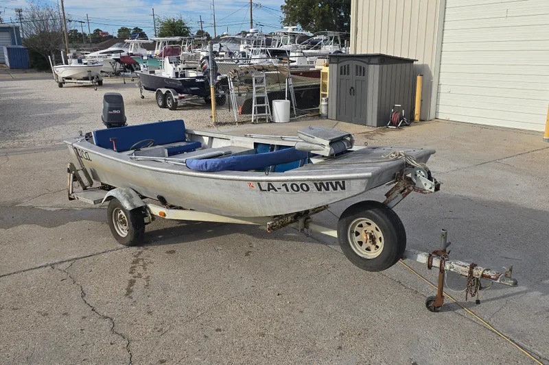 The Image of 1976 Custom Aluminum 16 boat on trailer in a marina parking lot. - 1