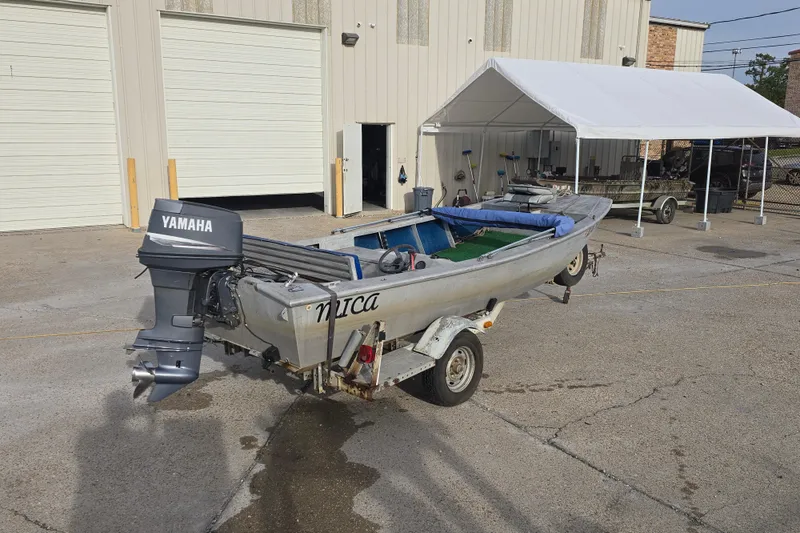 Slide: The Image of 1976 Custom Aluminum 16 boat with Yamaha motor on trailer, parked outside a garage. - 3