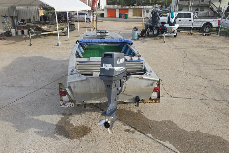 Slide: The Image of 1976 Custom Aluminum 16 boat with Yamaha outboard motor in a parking area. - 4