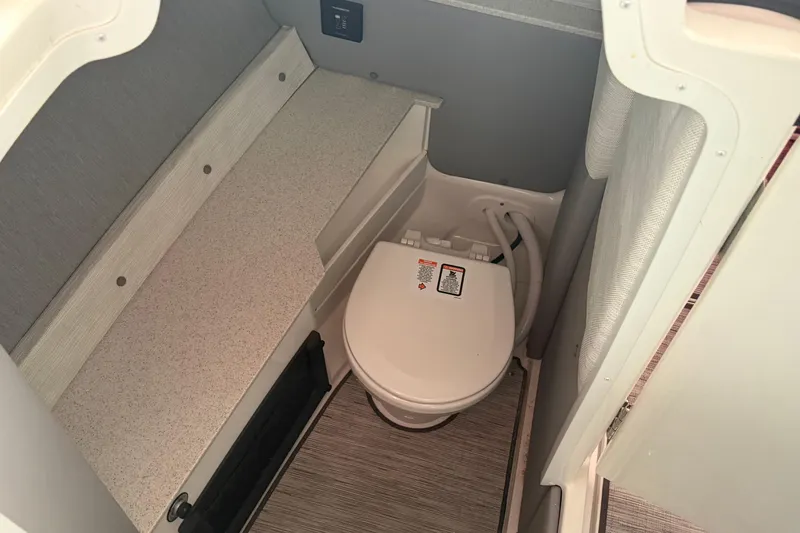 Slide: The Image of 2025 Cobalt R6 boat interior with compact marine toilet and storage area. - 16