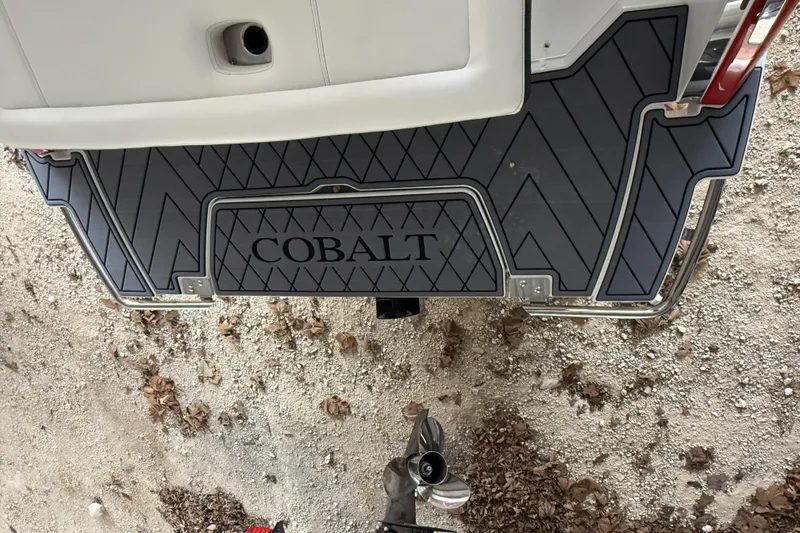 Slide: The Image of 2025 Cobalt R6 boat stern with custom mat on gravel surface. - 8