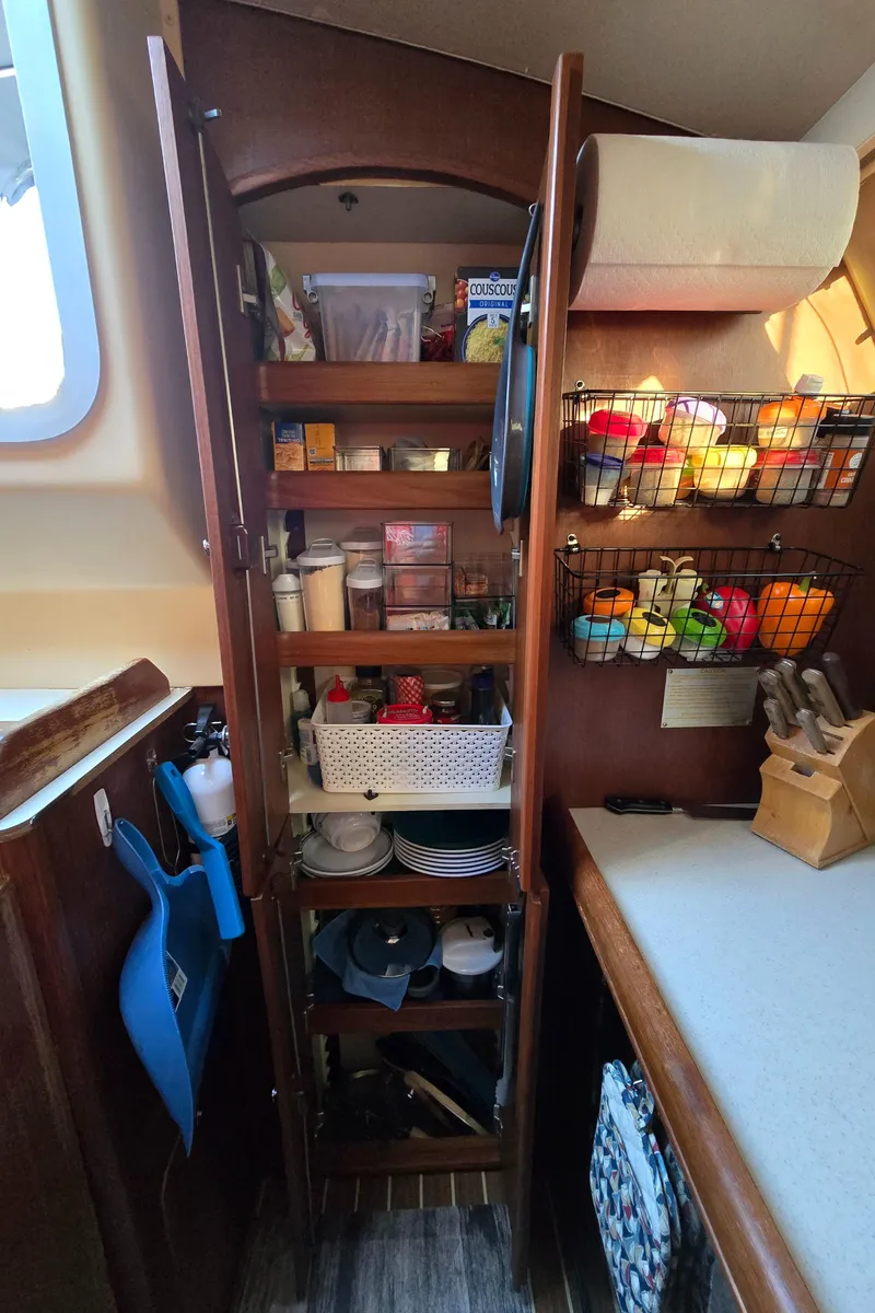 Slide: The Image of Wooden pantry in a 2004 Hunter 41 AC sailboat, stocked with kitchen essentials. - 25