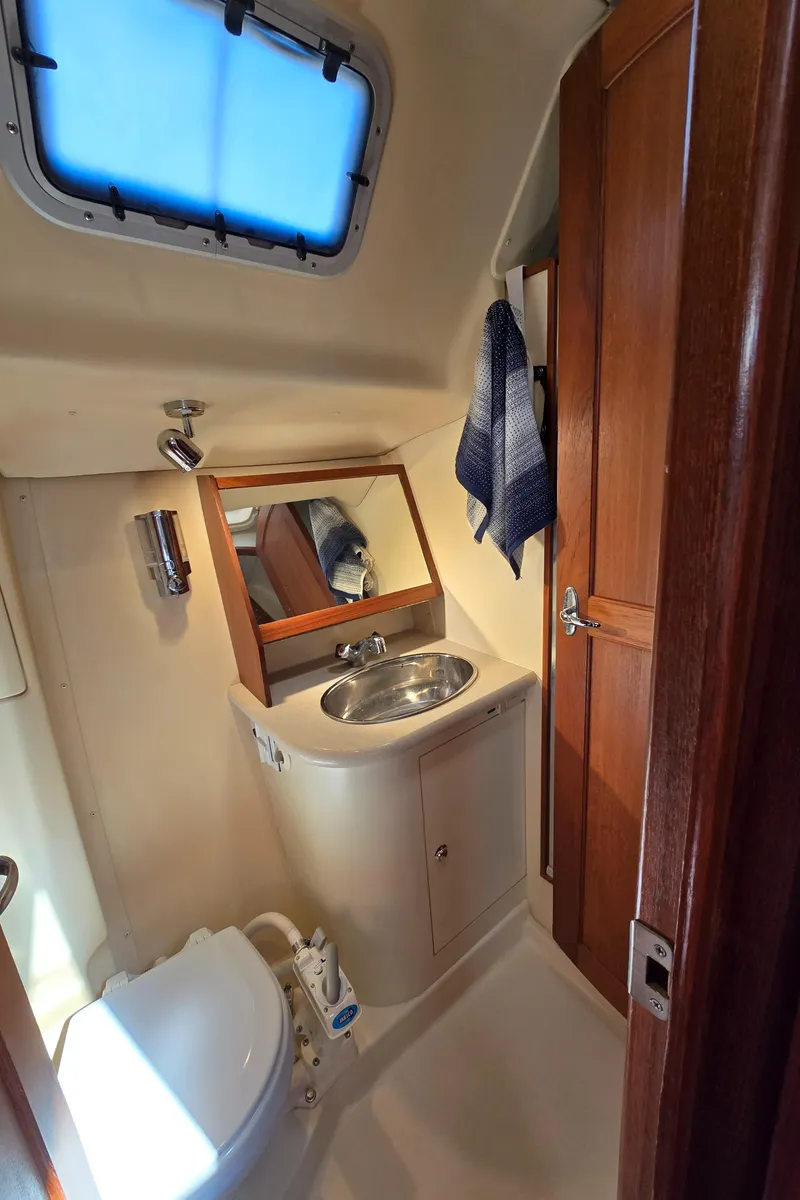 Slide: The Image of 2004 Hunter 41 AC yacht bathroom with sink, mirror, and wooden cabinetry. - 44