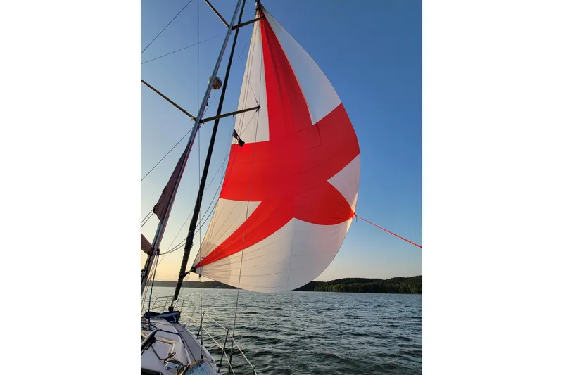 Slide: The Image of Sailboat with red and white spinnaker on a Hunter 41 AC, 2004 model, at sunset. - 5