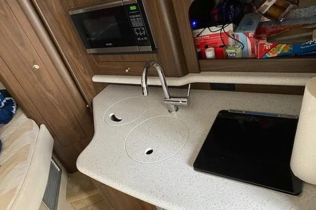 Slide: The Image of 2018 Rinker EX 320 boat kitchen with sink, microwave, and countertop. - 15