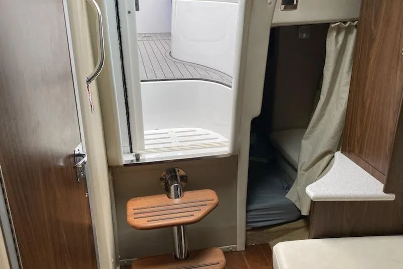 Slide: The Image of 2018 Rinker EX 320 cabin interior with wooden steps and cozy sleeping area. - 16