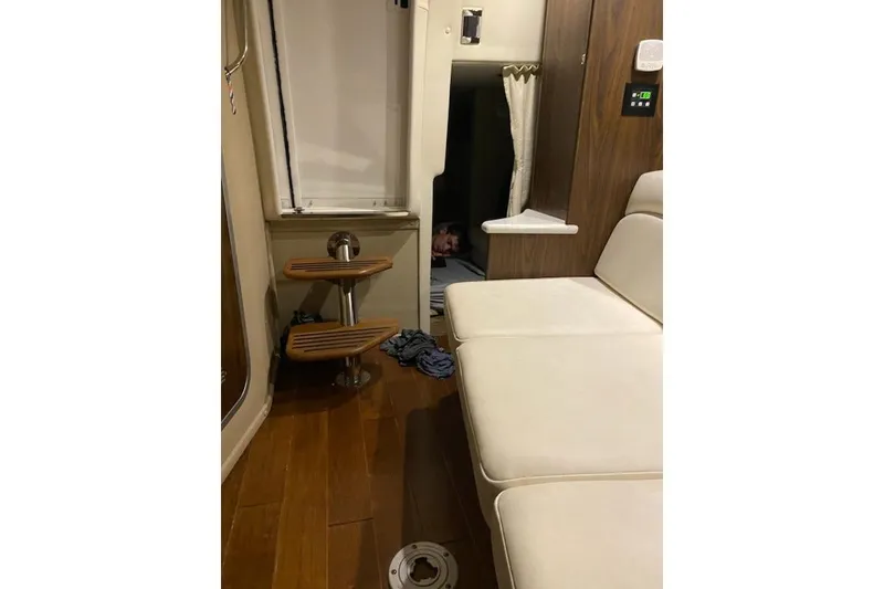 Slide: The Image of 2018 Rinker EX 320 cabin interior with wooden flooring and white seating. - 17