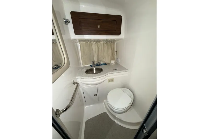 Slide: The Image of 2018 Rinker EX 320 boat bathroom with sink, toilet, and storage cabinet. - 18