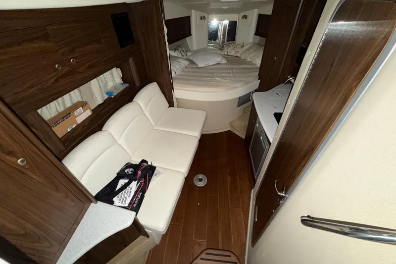 Slide: The Image of 2018 Rinker EX 320 cabin interior with white seating, wood accents, and cozy sleeping area. - 19