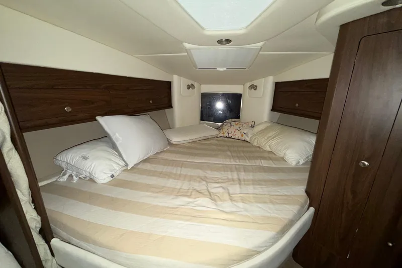 Slide: The Image of 2018 Rinker EX 320 cabin interior with cozy bed and wooden storage cabinets. - 20