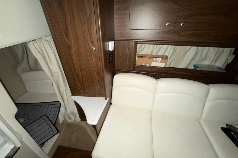 Slide: The Image of 2018 Rinker EX 320 cabin interior with white seating and wooden cabinetry. - 25