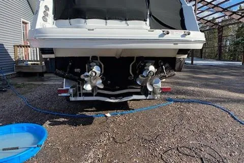 Slide: The Image of 2018 Rinker EX 320 boat rear view with dual propellers on a gravel surface. - 38