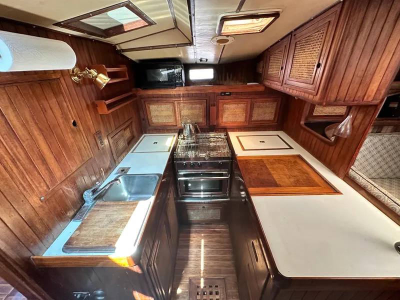 Slide: The Image of 1982 Pan Oceanic 43 yacht kitchen with wood cabinetry, stove, and sink. Cozy and functional design. - 21