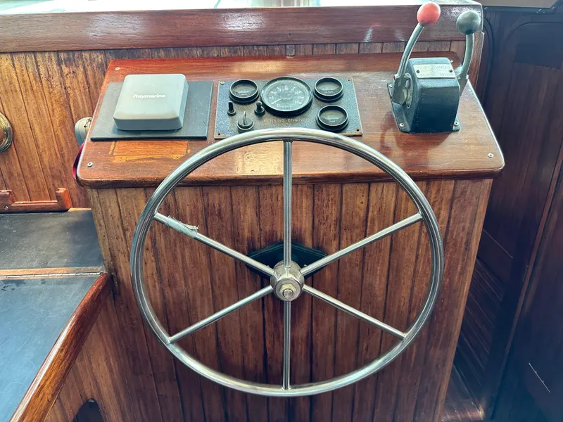 Slide: The Image of Steering wheel and controls of a 1982 Pan Oceanic 43 boat, featuring wooden paneling. - 28