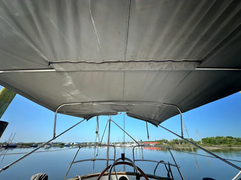 Slide: The Image of View from a 1982 Pan Oceanic 43 sailboat cockpit, overlooking calm waters and distant marina. - 7