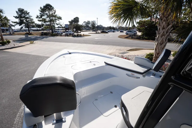 Slide: The Image of 2026 Sea Pro 250 Bay boat interior with seating, parked near palm trees. - 17