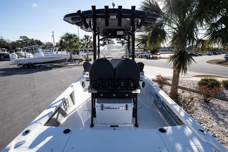 Slide: The Image of 2026 Sea Pro 250 Bay boat interior with seating, palm trees, and parked boats in the background. - 8