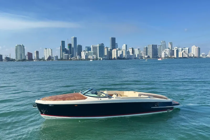 The Image of 2018 Chris-Craft Capri 27 boat on water with city skyline in background. - 0