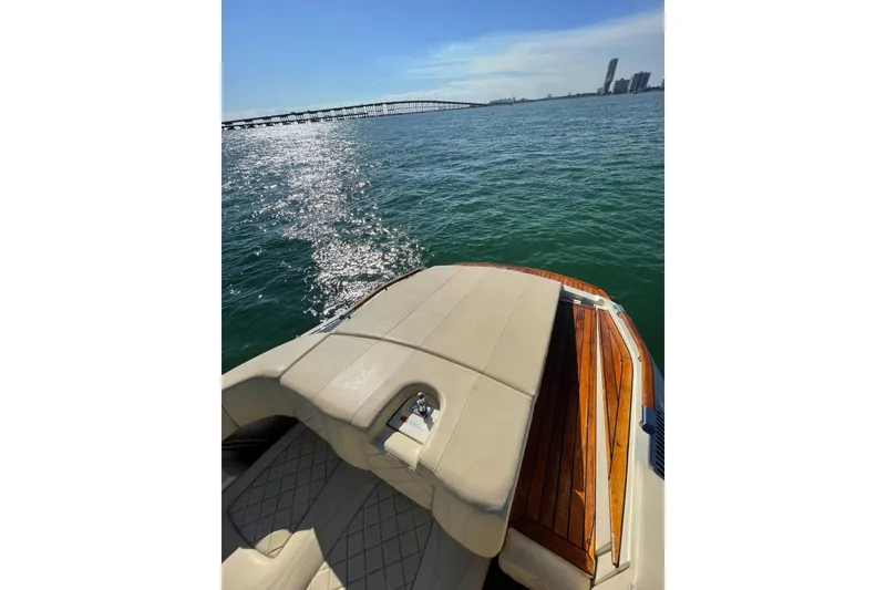 Slide: The Image of 2018 Chris-Craft Capri 27 boat on water, featuring elegant seating and wooden deck. - 10