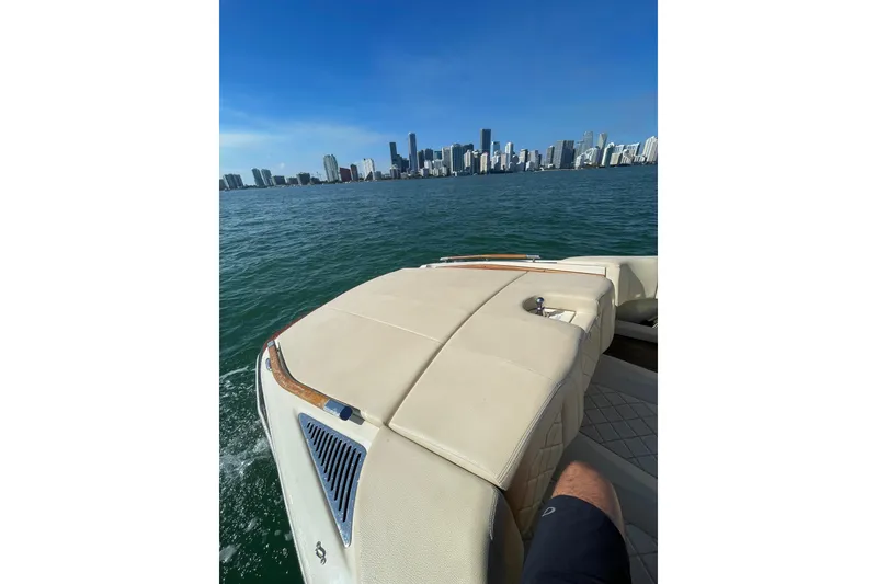 Slide: The Image of 2018 Chris-Craft Capri 27 cruising with city skyline in the background. - 11