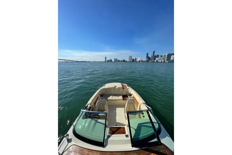 Slide: The Image of 2018 Chris-Craft Capri 27 boat cruising with city skyline in the background. - 4