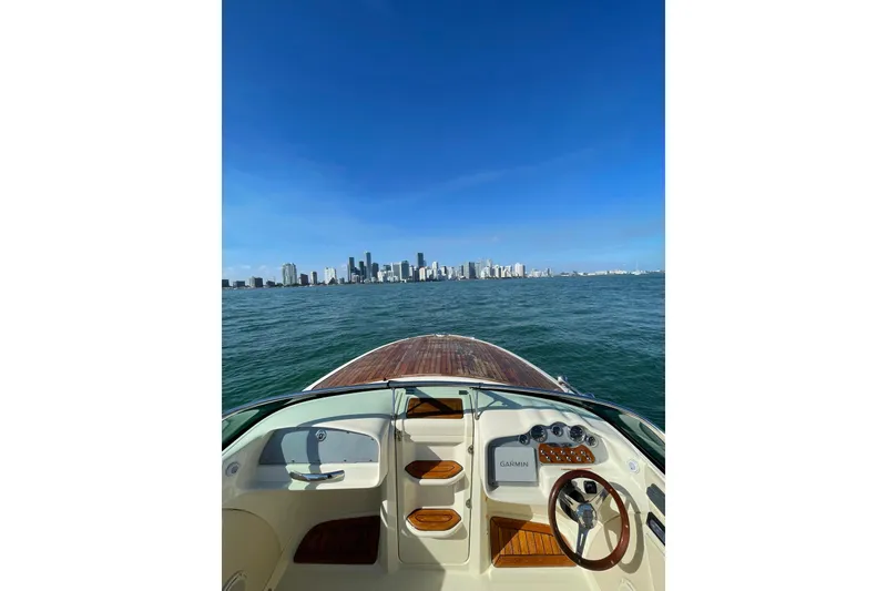 Slide: The Image of 2018 Chris-Craft Capri 27 boat cruising towards city skyline under clear blue sky. - 6