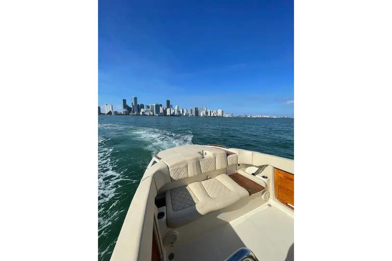 Slide: The Image of 2018 Chris-Craft Capri 27 cruising with city skyline in the background. - 9
