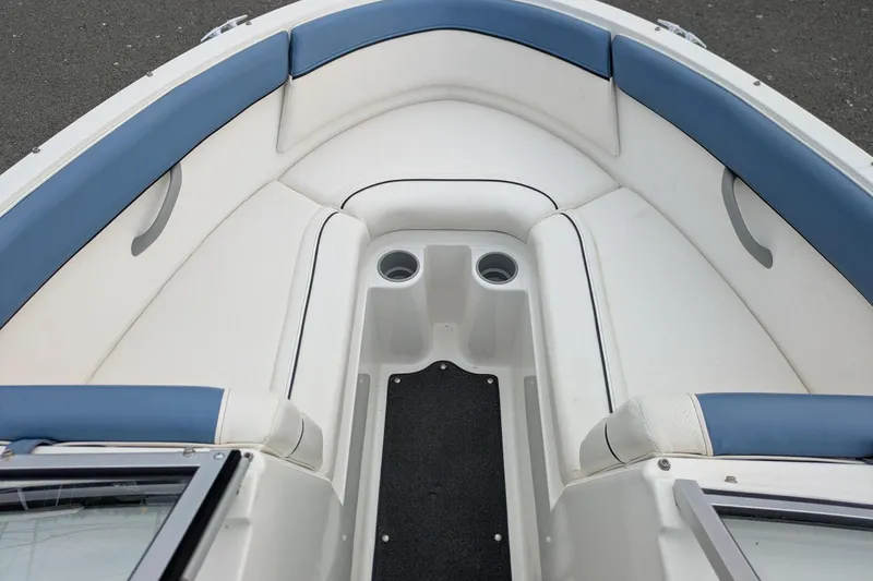 Slide: The Image of 2013 Bayliner 185 Bowrider interior with blue and white seating, cup holders, and carpeted floor. - 13