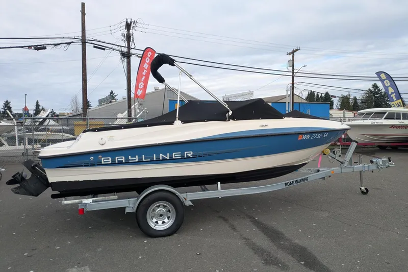 Slide: The Image of 2013 Bayliner 185 Bowrider on trailer, parked outdoors, with cover and visible branding. - 2