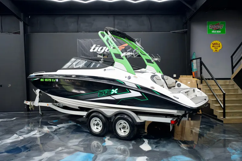 Slide: The Image of 2018 Yamaha Boats 212X in showroom, black and green design, on trailer. - 3