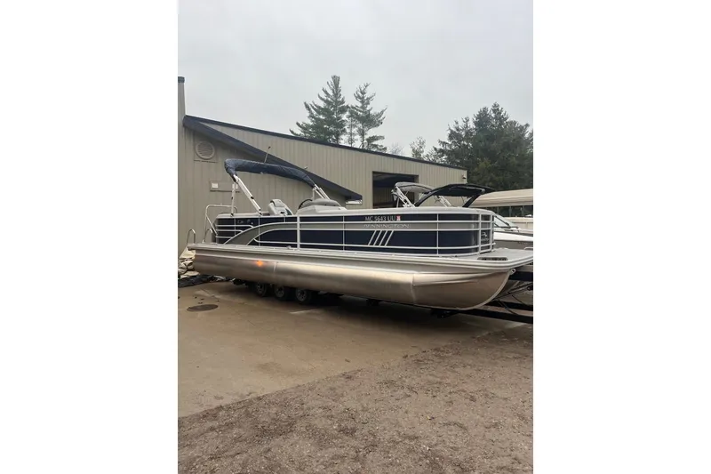 Slide: The Image of 2022 Bennington 25 LSR pontoon boat parked outdoors near a building. - 12