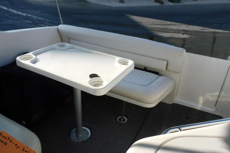 Slide: The Image of 2006 Monterey 302 Cruiser interior with white seating and table, featuring cup holders. - 29