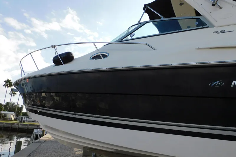 Slide: The Image of 2006 Monterey 302 Cruiser boat docked, featuring sleek black and white design. - 32