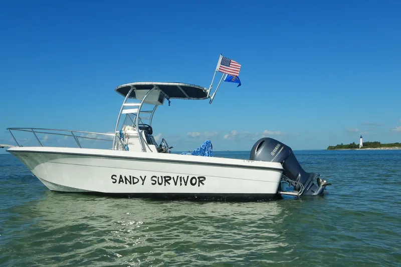 Slide: The Image of 2004 Hydra-Sports 212 CC boat named "Sandy Survivor" on water with lighthouse in background. - 2