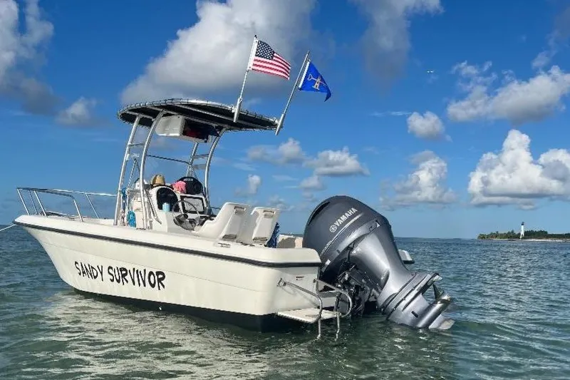 Slide: The Image of 2004 Hydra-Sports 212 CC boat named "Sandy Survivor" on water, with flags and Yamaha motor. - 31