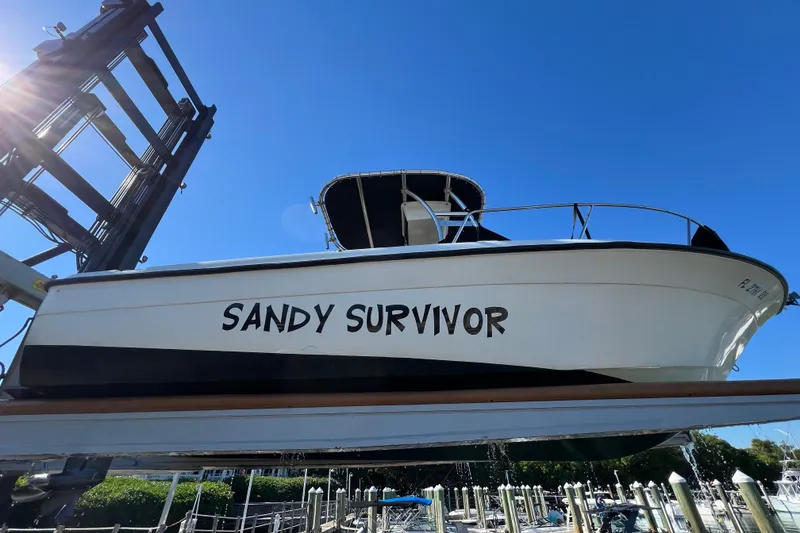 Slide: The Image of 2004 Hydra-Sports 212 CC boat named "Sandy Survivor" on a lift under clear blue sky. - 35