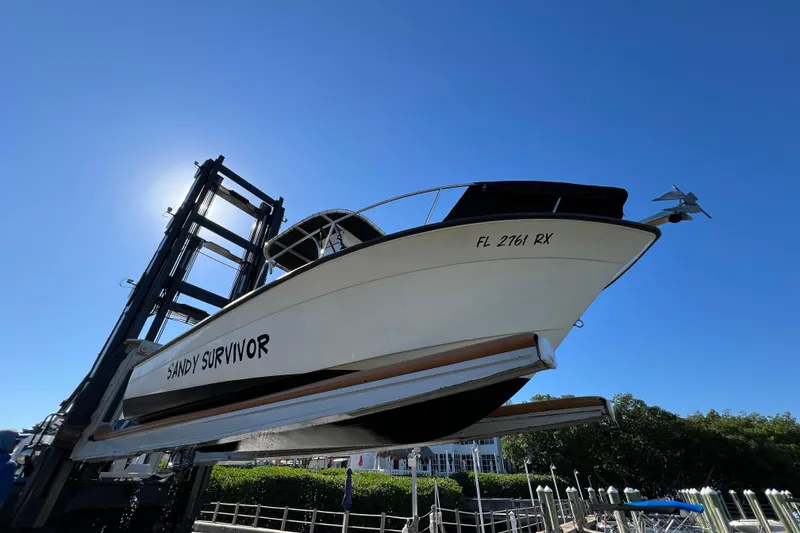 Slide: The Image of 2004 Hydra-Sports 212 CC boat named "Sandy Survivor" on a lift under clear blue sky. - 36