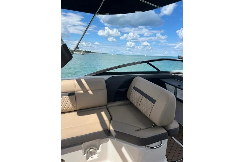 Slide: The Image of 2018 Sea Ray SLX-W 230 boat interior with beige seating, ocean view, and blue sky. - 16