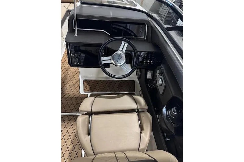 Slide: The Image of 2018 Sea Ray SLX-W 230 boat cockpit with steering wheel and beige seating. - 20