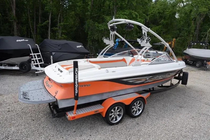 Slide: The Image of 2008 Tigé 24Ve boat with orange and white design on a trailer, parked outdoors. - 3