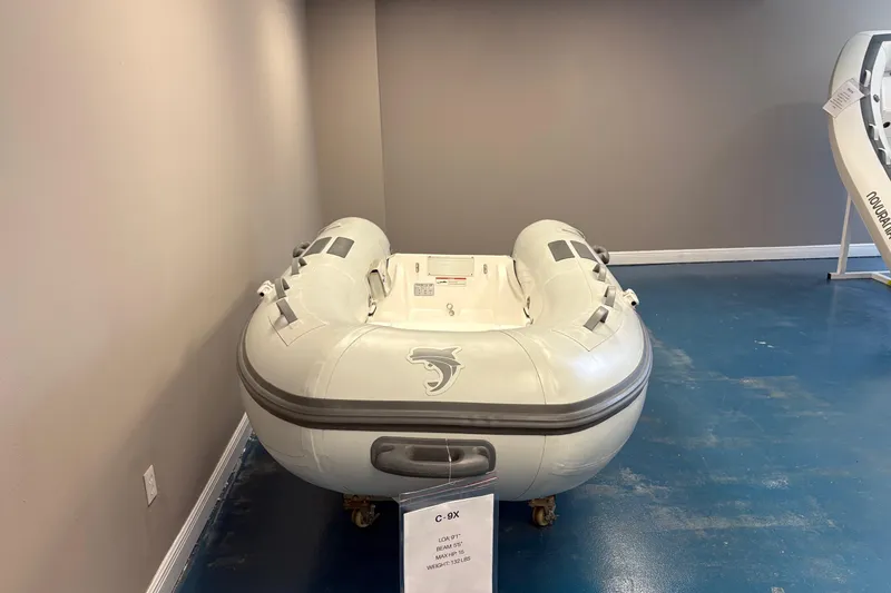 Slide: The Image of 2025 Caribe C9X inflatable boat displayed indoors on blue floor. - 4