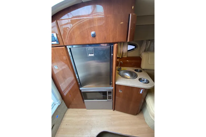 Slide: The Image of 2015 Formula 310 Sun Sport interior with kitchenette, featuring wood cabinetry and stainless steel appliances. - 19