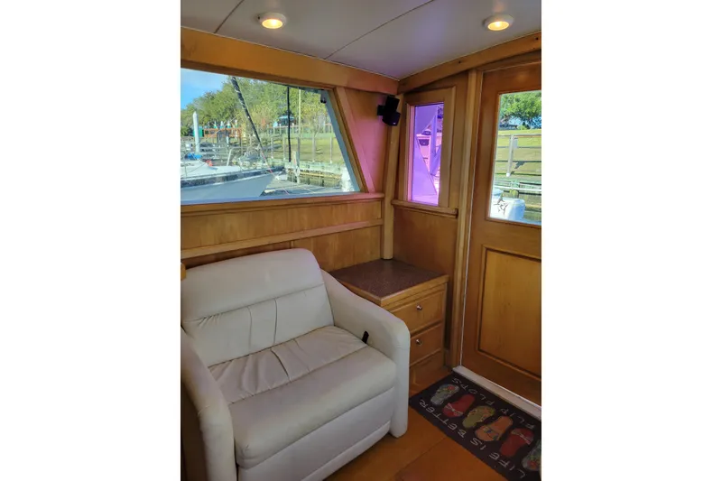 Slide: The Image of Interior of 1979 Bertram 38 Convertible yacht with white armchair and wooden paneling. - 10