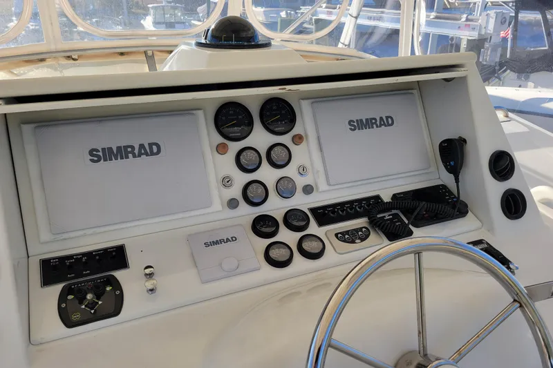 Slide: The Image of 1979 Bertram 38 Convertible boat dashboard with Simrad navigation equipment and steering wheel. - 32
