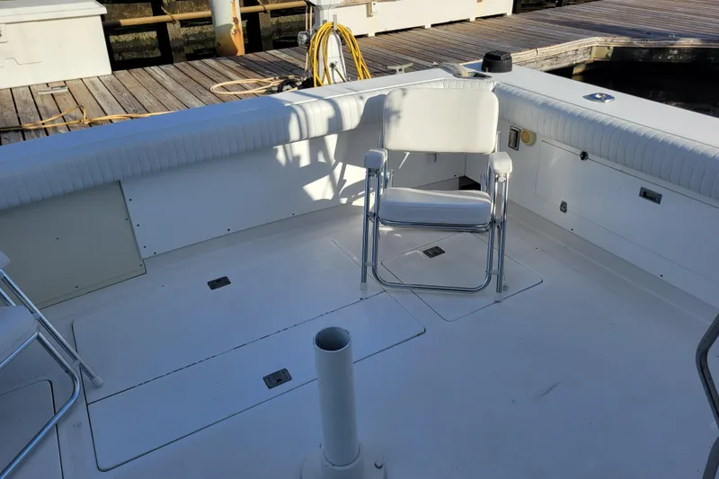Slide: The Image of 1979 Bertram 38 Convertible boat deck with white seating and dock view. - 45