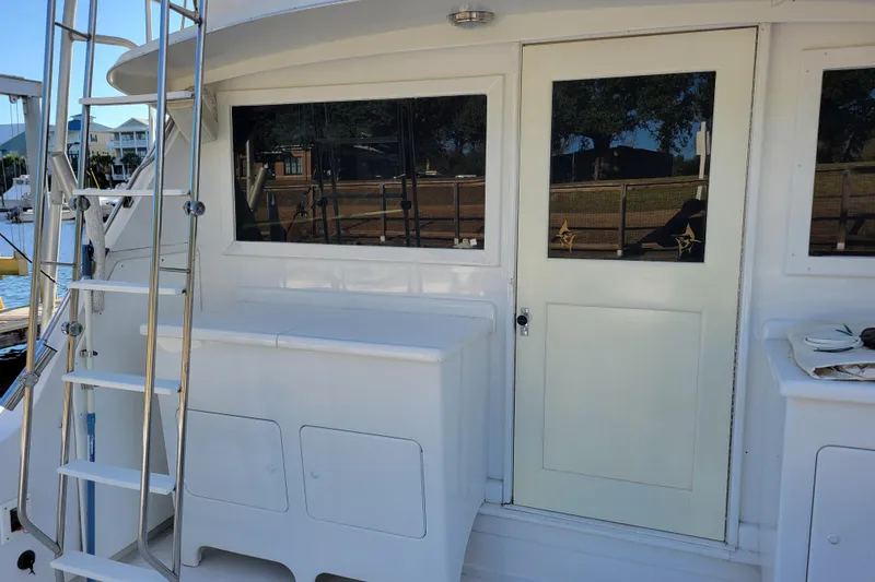 Slide: The Image of 1979 Bertram 38 Convertible yacht with ladder and cabin door, docked at marina. - 53