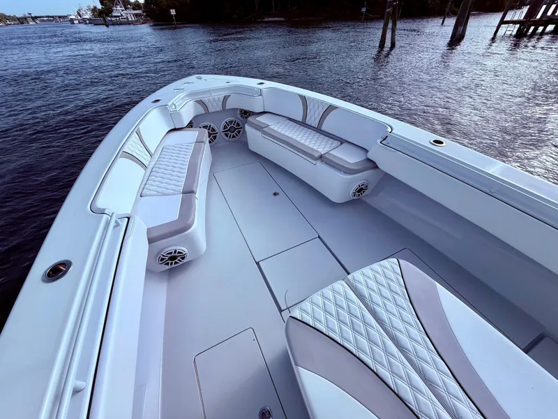 Slide: The Image of 2024 Contender 39 ST boat interior with cushioned seating and speakers on calm water. - 12