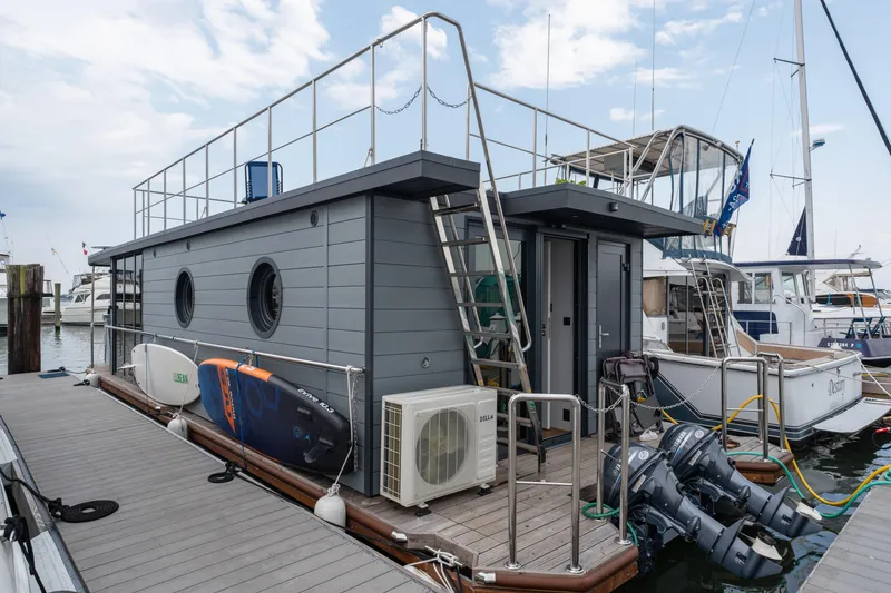 Slide: The Image of Modern Waterlodge Apart L Long houseboat docked, featuring rooftop access and outdoor equipment, 2026 model. - 26