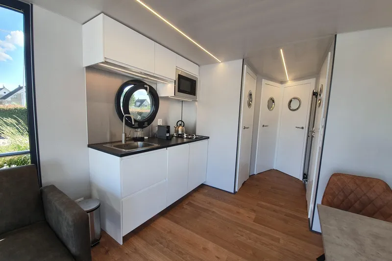 Slide: The Image of Modern Waterlodge Apart L Long 2026 interior with sleek kitchen and circular windows. - 28